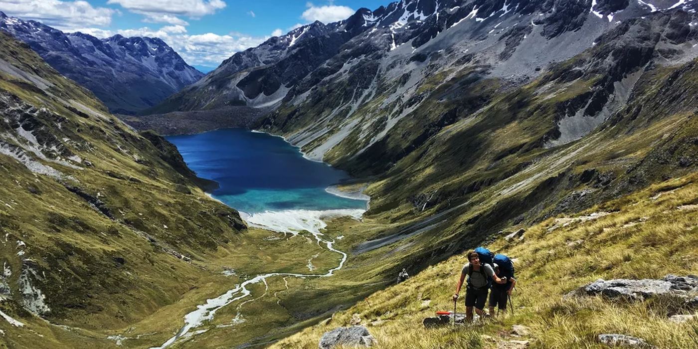 Two walkers descending toward a lake on Te Araroa